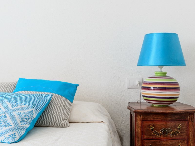 Bunte Nachttischlampe auf antikem Nachttisch nebem dem Doppelbett in Casa Grazia Bunte Nachttischlampe auf antikem Nachttisch nebem dem Doppelbett in Casa Grazia