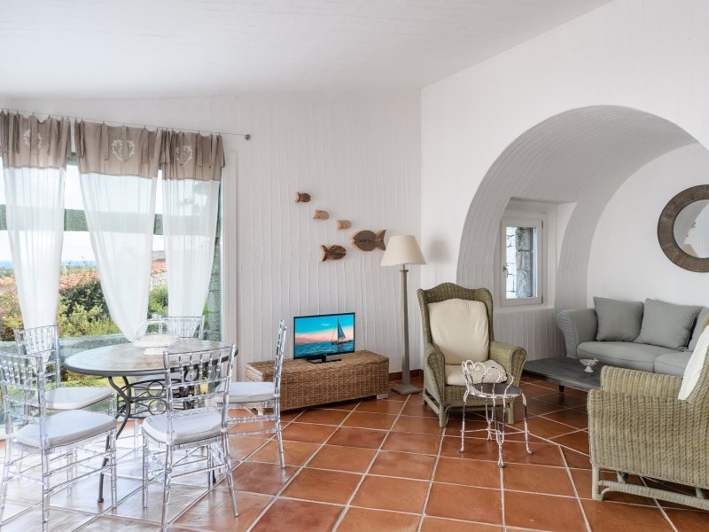 Wohnzimmer mit Panoramafenster, rundem Tisch mit Stühlen, TV und Sofaecke unter einem großen Wandbogen Wohnzimmer mit Panoramafenster, rundem Tisch mit Stühlen, TV und Sofaecke unter einem großen Wandbogen