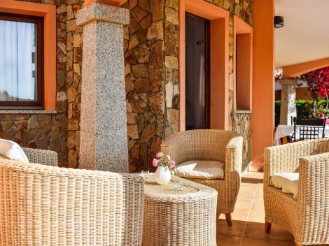 Auf der überdachten Terrasse stehen gemütliche Loungemöbel